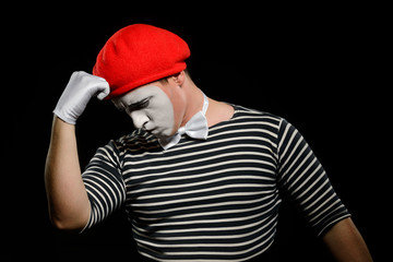 Thoughtful mime, isolated on black. Dressed in black and white striped t-shirt