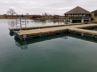 Boat dock over lake with large gazebo in background at public park
