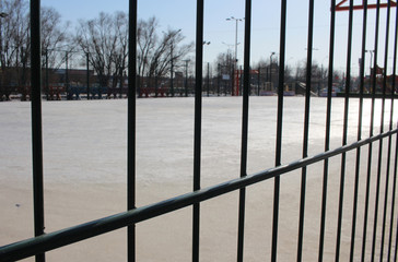 the covered sports ground in the street stadium for playing football behind an iron fence made of lattice is closed