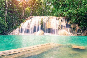 Waterfall, green forest in Erawan National Park, Thailand. Landscape with water flow, river, stream and rock at outdoor. Beautiful scenery of nature for tourist to tour, visit, relax in vacation.