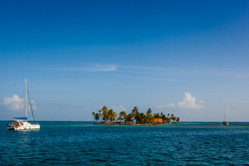 Fototapeta na wymiar Catamaran and palm fringed island in blue ocean water