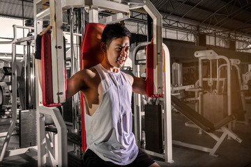 Man doing fitness training on a butterfly machine with weights in a gym