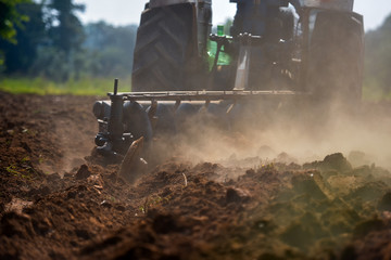Farmer in tractor preparing land with seedbed cultivator as part of pre seeding activities in early spring season of agricultural works at farmlands.