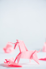 Pink origami unicorn with crumpled paper balls. Creative process is writing, light background