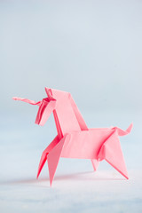 Pink origami unicorn on a light background
