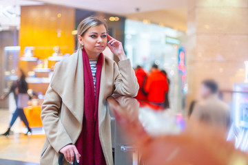 At the mall lifestyle fashion portrait of stunning brunette girl. Walking on At the mall. Going shopping. Wearing stylish white fitted coat, red neckscarf, black umbrella cane. Business woman.