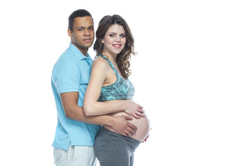 Handsome Afro American man and his beautiful pregnant wife are hugging and smiling while. Isolated white background.