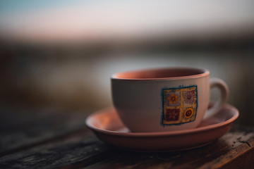 Tea or coffee cup with flower decor on the table in the outside.