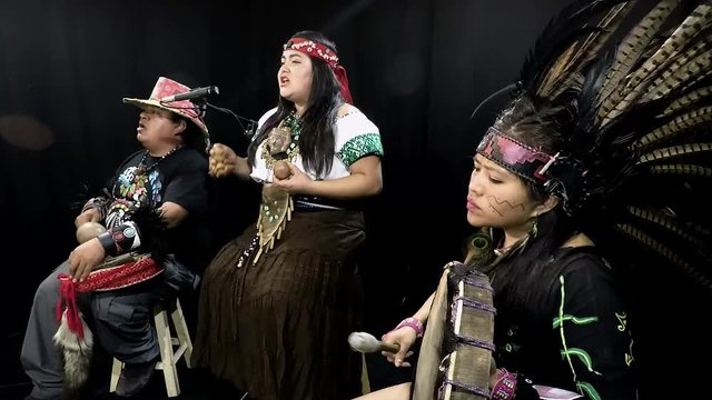 group of shaman Teotihuacanos, Xicalanca - Toltec in black background, with traditional dress dance with a trappings with feathers and drum