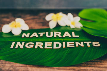 beauty industry and ethical vegan products, Natural Ingredients message on tropical banana leaf with monoi flowers