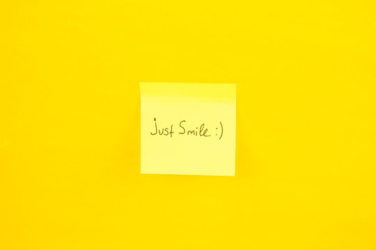 Yellow sticker that says just smile on an orange background.