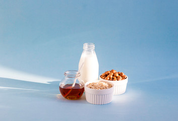 Healthy breakfast. Milk, honey, nuts and oatmeal on a blue background in the sunshine