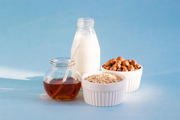 Healthy breakfast. Milk, honey, nuts and oatmeal on a blue background in the sunshine