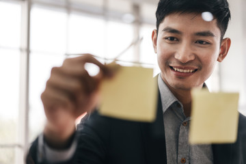 Happy smile adult businessman use post it at office.
