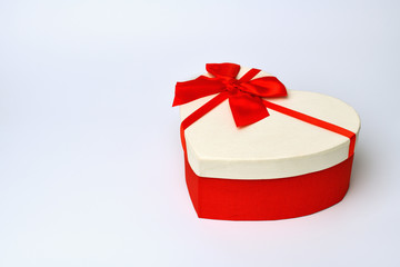 Box. Heart-shaped gift box with red ribbon  lies  on the right, left empty space for text on a blue-gray background. Valentine's day and Birthday