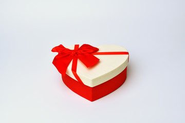 Box. Heart-shaped gift box with red ribbon stands in the middle on a blue-gray background. Valentine's day and Birthday