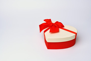 Box. Heart-shaped gift box with red ribbon  lies  on the right, left empty space for text on a blue-gray background. Valentine's day and Birthday