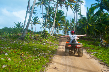 A group of people have fun on safari on quad bikes through the coconut beach near the shore