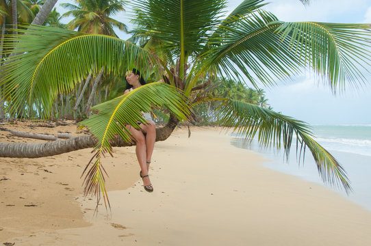 Girl on the palm tree on the beach