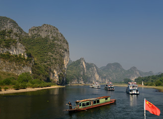 Cruise ships and rusted barge on the Li River Guangxi China with karst dome mountains