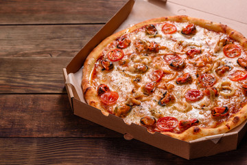 Tasty sliced pizza with seafood and tomato on a concrete background
