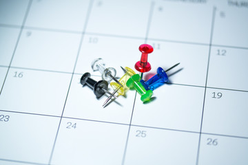 Colored pushpins spread on a calendar