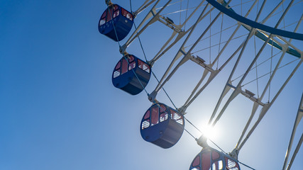 Blue ferris wheel with sun beam and clear blue sky background