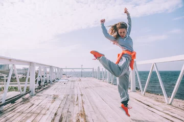 Deurstickers Hip hop dancer in fashion sportswear jumping and dancing in the street © Alena Ozerova