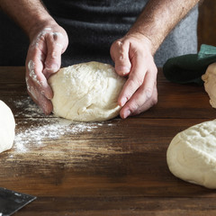 Man preparing dough for bread in bakery close up