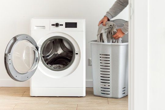 Side view putting clothes in washing machine in the home laundry