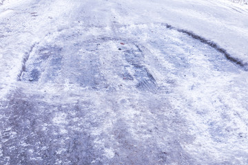 The bad asphalt winter road or way with ice, snow, puddles, pools, mud and slush