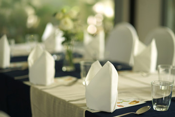 white table napkin folding into the boat shape on dining table