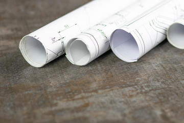 Wooden background. On it are blueprints or a plan of the future home or knowledge. They are rolled...