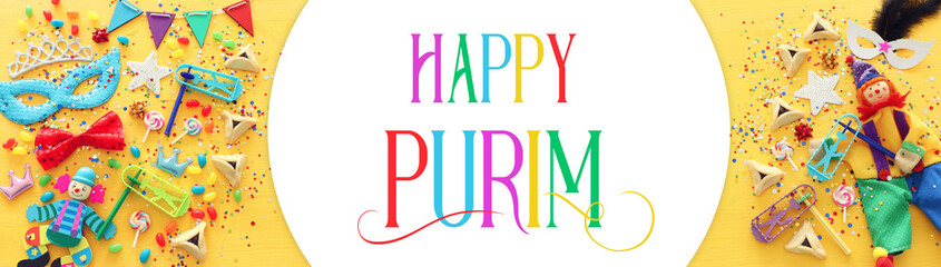 Purim celebration concept (jewish carnival holiday) over yellow wooden background. Top view, Flat lay