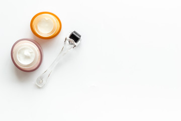 Dermaroller for mesotherapy near creams on white background top-down copy space