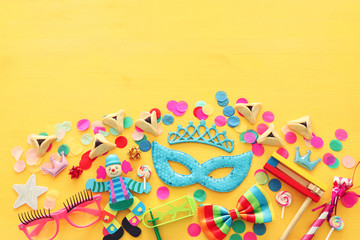 Fototapeta na wymiar Purim celebration concept (jewish carnival holiday) over yellow wooden background. Top view, Flat lay
