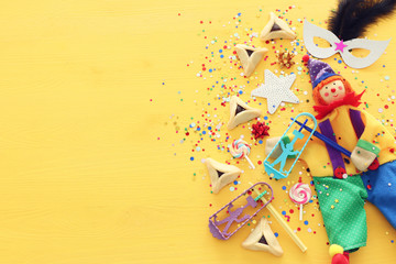 Purim celebration concept (jewish carnival holiday) over yellow wooden background. Top view, Flat lay