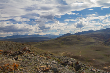 Panoramic view of an Altai mountain with white clouds. Stones on front view.
