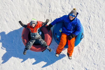 Father and son snow tubing in the winter in Canada - obrazy, fototapety, plakaty