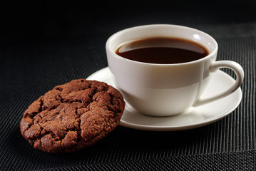 Cup of coffee and cookies on a black napkin