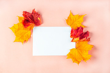 Invitation card mockup. Template blank greeting card to the wedding, birthday and other events. Paper on peach color background with dry autumn leaves.