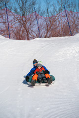 Fototapeta na wymiar Father and son snow tubing in the winter in Canada