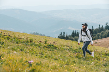 woman with backpack hiking in mountains