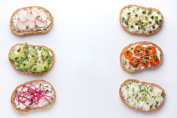 Fototapeta na wymiar Different sandwiches with grain bread, vegetables and microgreens on a white background