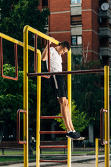 Fototapeta na wymiar Fitness man doing pull-ups on horizontal bar in the outdoors gym