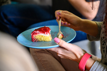 Woman eats fruit cake, holding the plate and fork in her hand