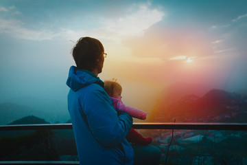 father and baby looking at sunset in mountains