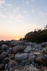 Sunrise view around stones in the coastline.