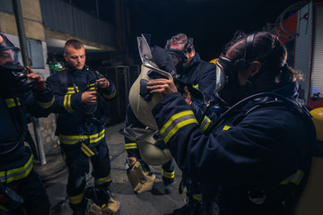 Group of firefighters standing inside the fire brigade wearing helmet and protective uniform