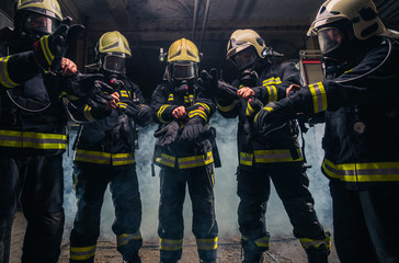 Team of firefighters in the fire department wearing gas masks and uniform